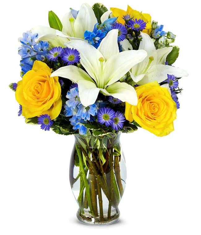 Yellow roses, blue delphinium and white lilies in a vase for Mothers Day